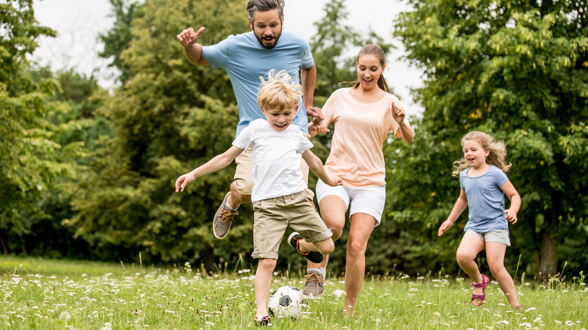 Family Playing Football in a Field