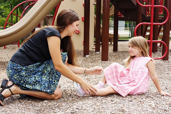 Lady helping injured girl in a playground